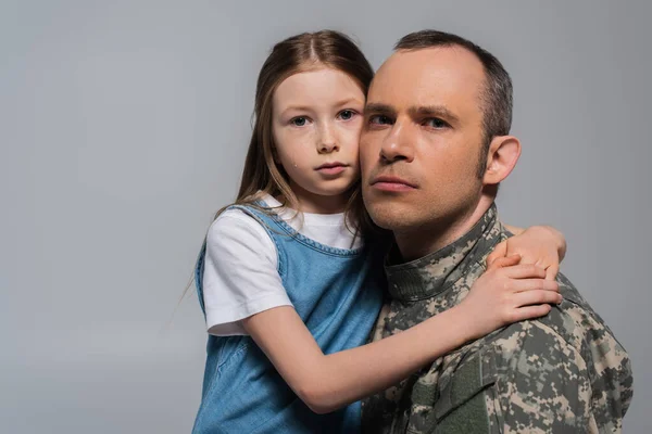 Патріотична дитина обіймає військового в уніформі і плаче під час пам'ятного дня ізольовано на сірому — стокове фото