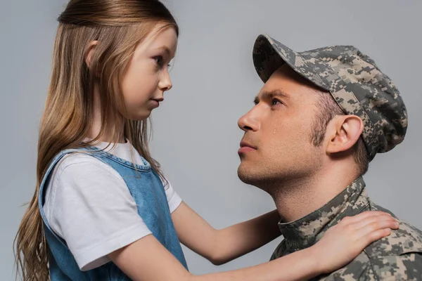 Sad girl looking at serviceman in military uniform crying during memorial day isolated on grey — Stock Photo
