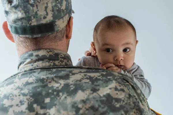 Father in military uniform and cap hugging newborn son isolated on grey — Stock Photo