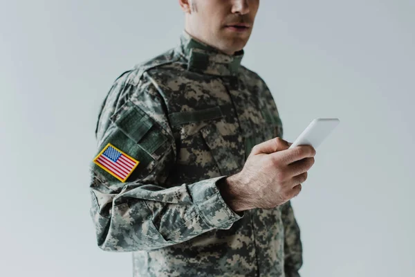 Vista cortada de americano serviceman usando smartphone isolado em cinza — Fotografia de Stock