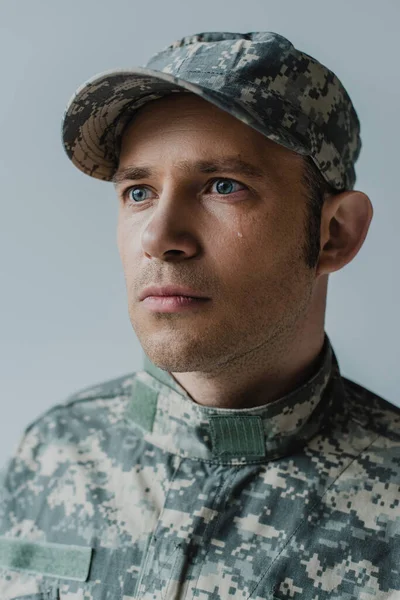 Triste soldado en uniforme militar llorando durante el día conmemorativo aislado en gris - foto de stock