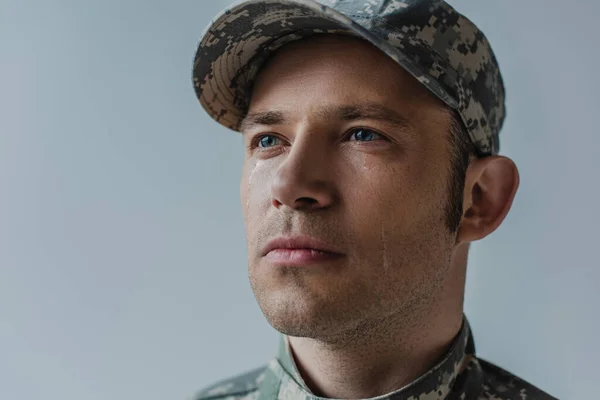Храбрый солдат в военной форме со слезой на лице, изолированной от серого — стоковое фото