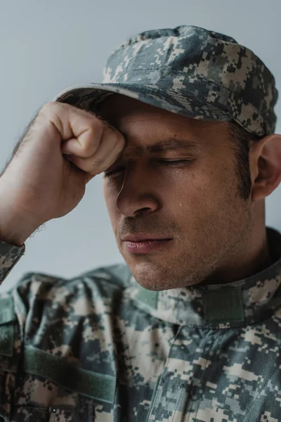 Sad soldier in military uniform crying with closed eyes during memorial day isolated on grey — Stock Photo