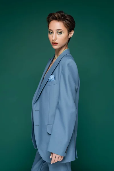 Стильна жінка в синьому формальному одязі позує на бірюзовому зеленому фоні — Stock Photo