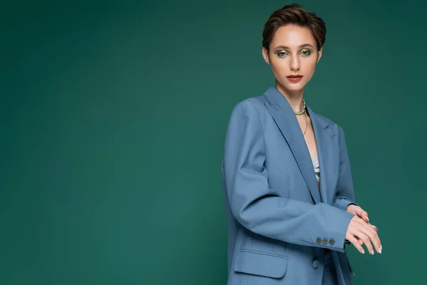 Young woman with short hair posing in blue blazer on turquoise green background — Stock Photo
