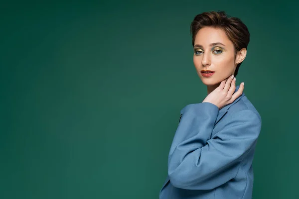 Charming young woman with short hair posing in blue suit on turquoise green background — Stock Photo