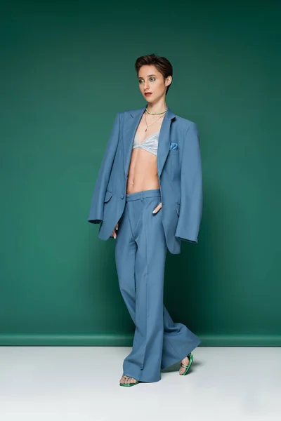 Full length of young woman with short hair posing in blue pantsuit on turquoise green background — Stock Photo