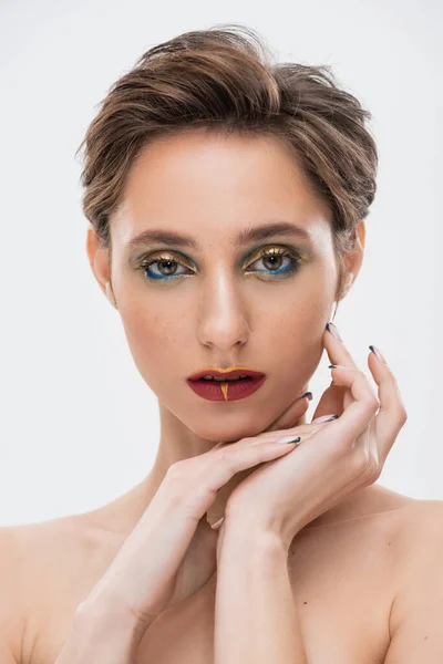Junge Frau mit kurzen Haaren und hellem Make-up blickt vereinzelt in die Kamera auf grau — Stockfoto