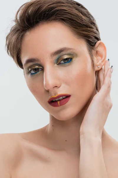 Porträt einer jungen Frau mit leuchtenden Augen Make-up Fixierung Hemdhaar und Blick in die Kamera isoliert auf grau — Stockfoto