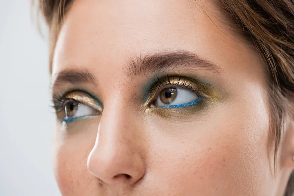 Nahaufnahme einer jungen Frau mit glänzendem Augen-Make-up und kurzen, auf grau isolierten Haaren — Stockfoto