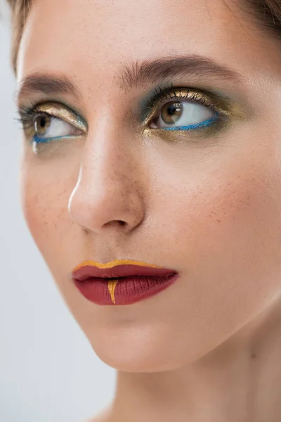 Gros plan de jeune femme avec maquillage brillant des yeux et lèvres rouges isolées sur gris — Photo de stock