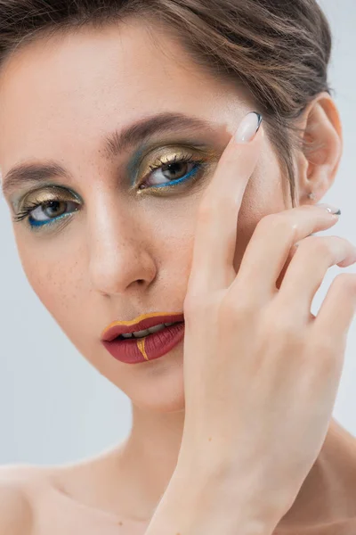 Nahaufnahme einer jungen Frau mit goldenem und blauem Augen-Make-up isoliert auf grau — Stockfoto