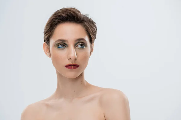 Portrait of young woman with shiny makeup and short hair isolated on grey — Stock Photo