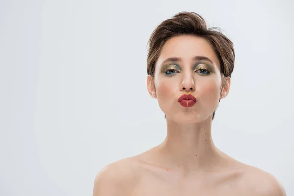 Porträt einer jungen Frau mit glänzendem Make-up und kurzen, schmollenden Lippen, isoliert auf grau — Stockfoto