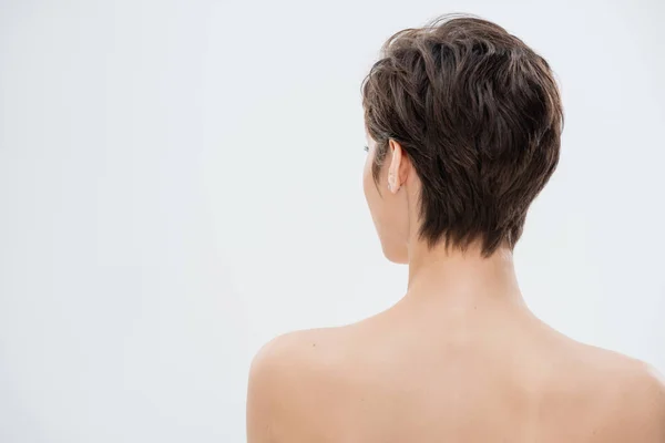 Vista posteriore di giovane donna con capelli corti e spalle nude isolate su grigio — Foto stock