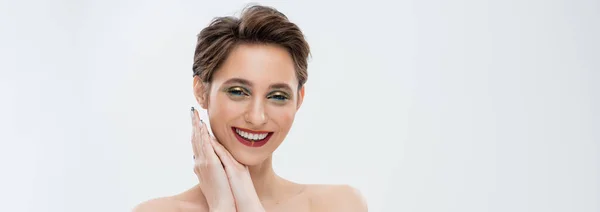 Fröhliche junge Frau mit schimmerndem Augen-Make-up, lächelnd isoliert auf grau, Banner — Stockfoto