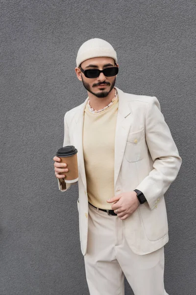 Fashionable gay man in beige suit and sunglasses holding paper cup outdoors — Stock Photo