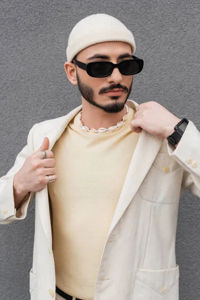 Fashionable gay man in jacket and sunglasses standing outdoors — Stock Photo