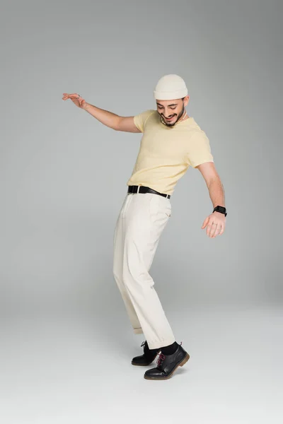 Longitud completa de hombre gay de moda y alegre posando sobre fondo gris - foto de stock