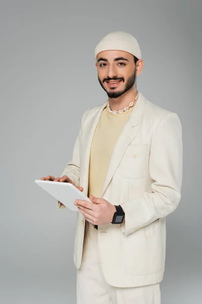 Positivo y elegante gay hombre celebración digital tablet aislado en gris - foto de stock