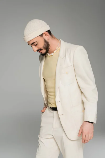 Hombre homosexual de moda en traje y sombrero posando aislado en gris - foto de stock