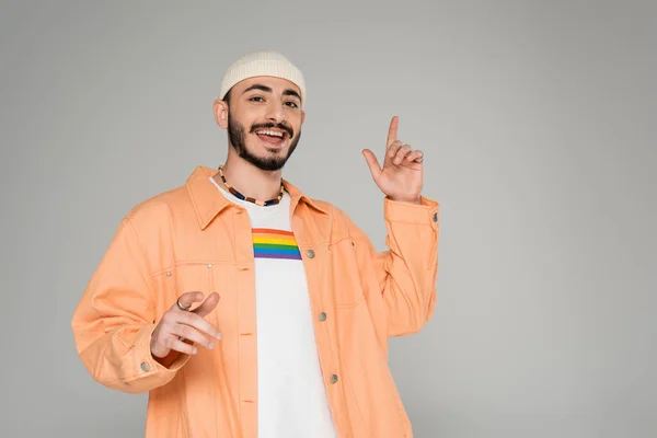 Elegante hombre gay con bandera lgbt en camiseta apuntando con los dedos aislados en gris - foto de stock