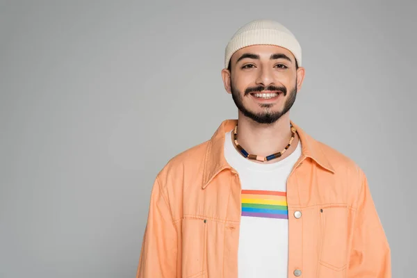 Lächelnder und stilvoller schwuler Mann mit lgbt-Flagge auf T-Shirt, der isoliert auf grau in die Kamera blickt — Stockfoto