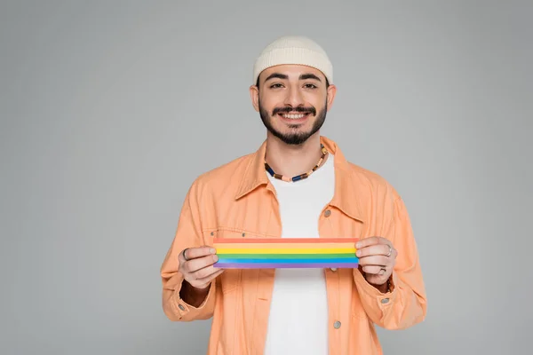 Fröhlicher homosexueller Mann mit lgbt-Fahne und Blick in die Kamera isoliert auf grau — Stockfoto