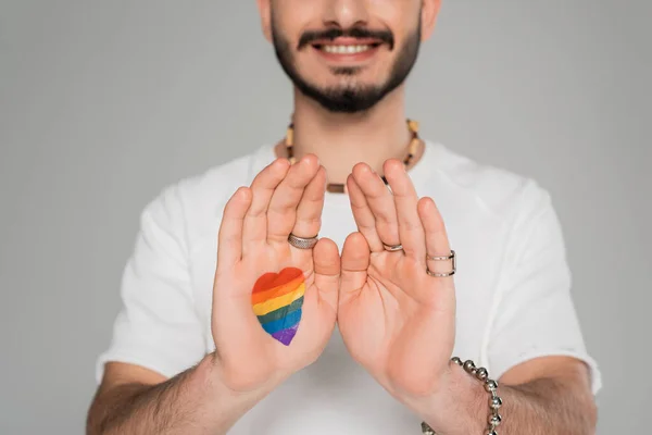 Обрезанный вид веселого гея с флагом lgbt на руке изолирован в серый, Международный день борьбы с гомофобией — стоковое фото