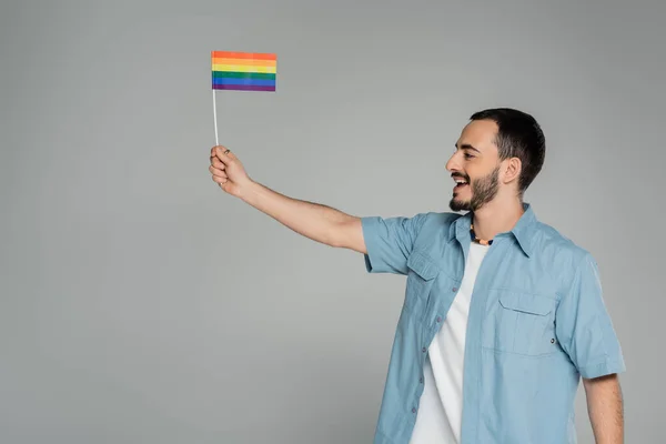 Vista lateral do homem homossexual alegre segurando bandeira lgbt e olhando para longe isolado no cinza — Fotografia de Stock