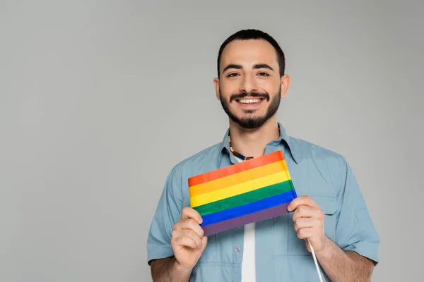 Retrato de alegre gay homem no camisa segurando lgbt bandeira isolado no cinza — Fotografia de Stock