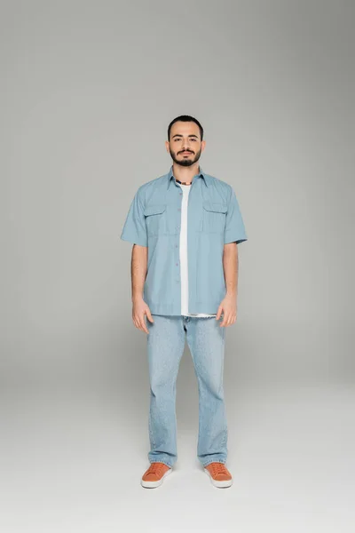 Stilvoller schwuler Mann im Jeanshemd blickt in die Kamera auf grauem Hintergrund — Stockfoto