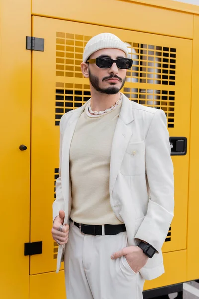Homme homosexuel élégant en costume beige et lunettes de soleil debout sur la rue urbaine — Photo de stock