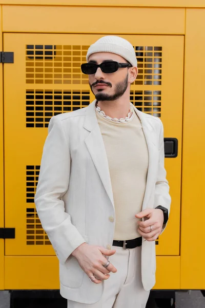 Homme homosexuel à la mode en chapeau et lunettes de soleil debout sur la rue urbaine — Photo de stock