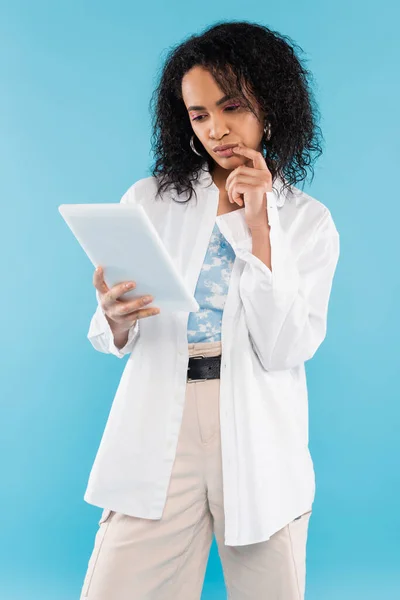 Mulher americana africana pensativo em camisa elegante branco olhando para tablet digital isolado em azul — Fotografia de Stock