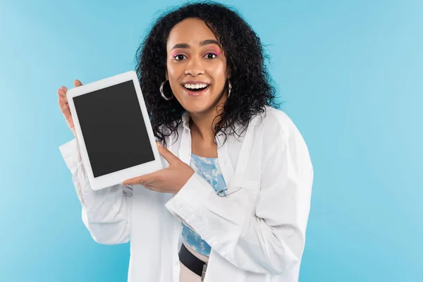 Mulher americana africana surpreendente mostrando tablet digital com tela em branco na câmera isolada em azul — Fotografia de Stock