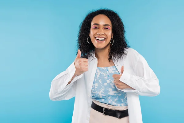 Overjoyed and stylish african american woman showing thumbs up isolated on blue — Stock Photo