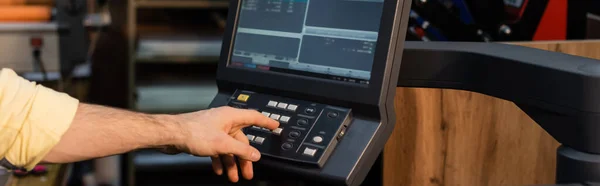 Vista recortada del hombre presionando el botón en el panel cerca del monitor en el centro de impresión, bandera - foto de stock