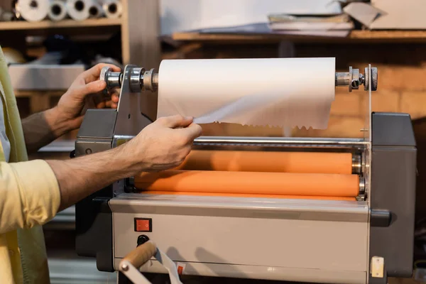 Visão recortada do trabalhador puxando papel enquanto trabalhava com plotter de impressão — Fotografia de Stock