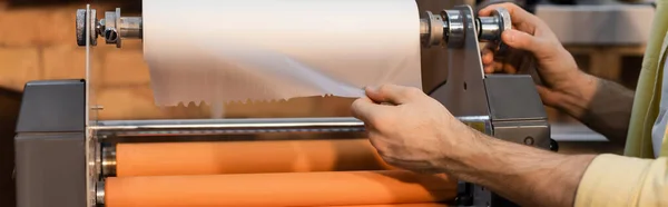 Обрезанный вид рабочего тянет бумагу при работе с печатным плоттером, баннером — стоковое фото