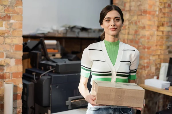 Charming publisher holding carton box in modern print center — Stock Photo