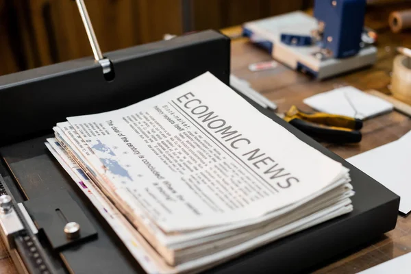 Printed newspapers with economic news inside of professional paper trimmer machine — Stock Photo