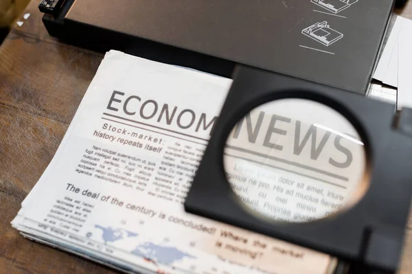 Lupa sobre jornais com notícias econômicas no centro de impressão — Fotografia de Stock
