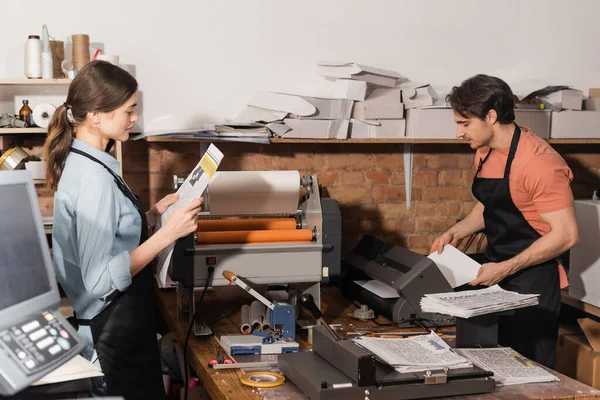 Симпатичная типографша читает газету рядом с коллегой в типографии — стоковое фото