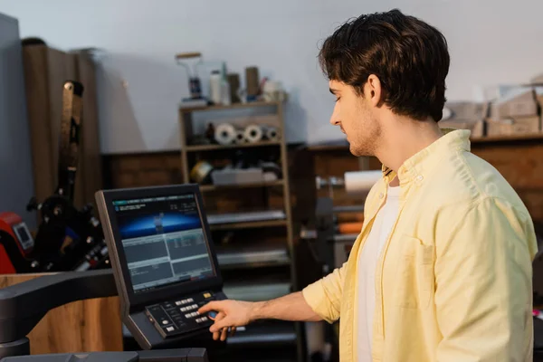 Editor em camisa amarela pressionando botão no painel perto do monitor — Fotografia de Stock