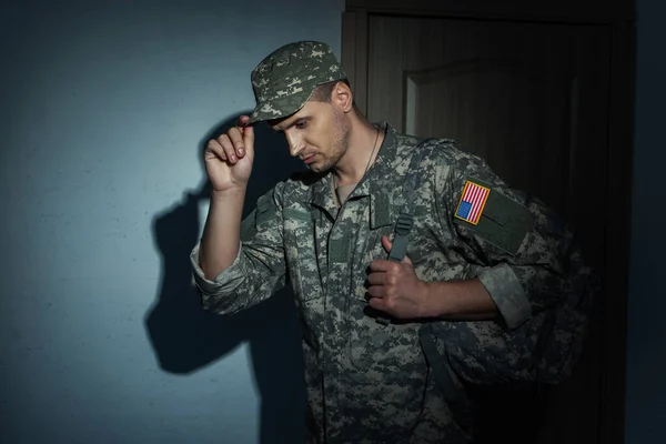 American military man taking off cap while coming back home at night — Stock Photo