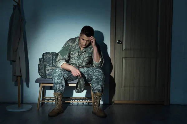 Depressed military veteran sitting in hallway on bench at night — Stock Photo