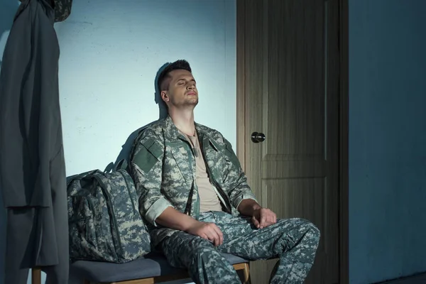 Military soldier with anxiety sitting in hallway on bench at night — Stock Photo