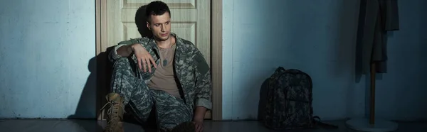Soldat avec trouble de stress post-traumatique assis près de la porte dans le couloir à la maison, bannière — Photo de stock
