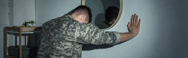 Soldier in uniform with mental problem standing near mirror at home at night, banner — Stock Photo